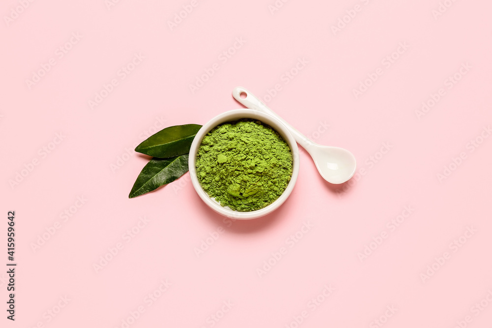 Bowl with powdered matcha tea and spoon on color background