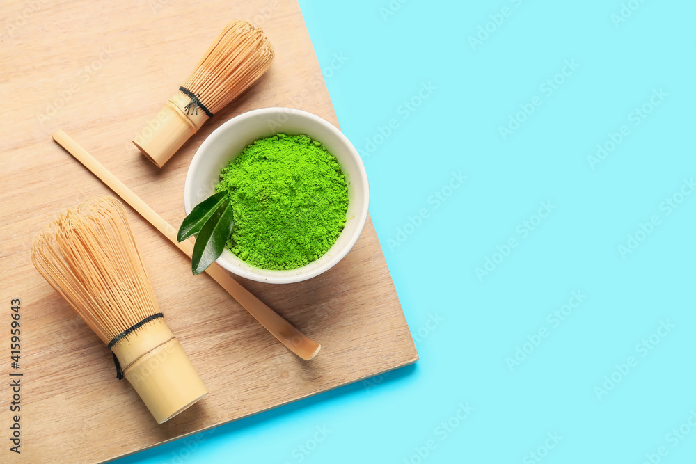 Powdered matcha tea, chasens and chashaku on color background