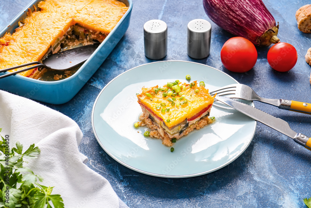 Plate of tasty baked casserole with vegetables on color background