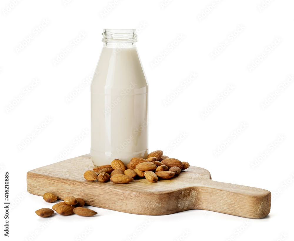 Board with bottle of tasty almond milk on white background