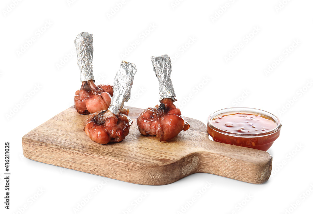 Board with tasty chicken lollipops and sauce on white background