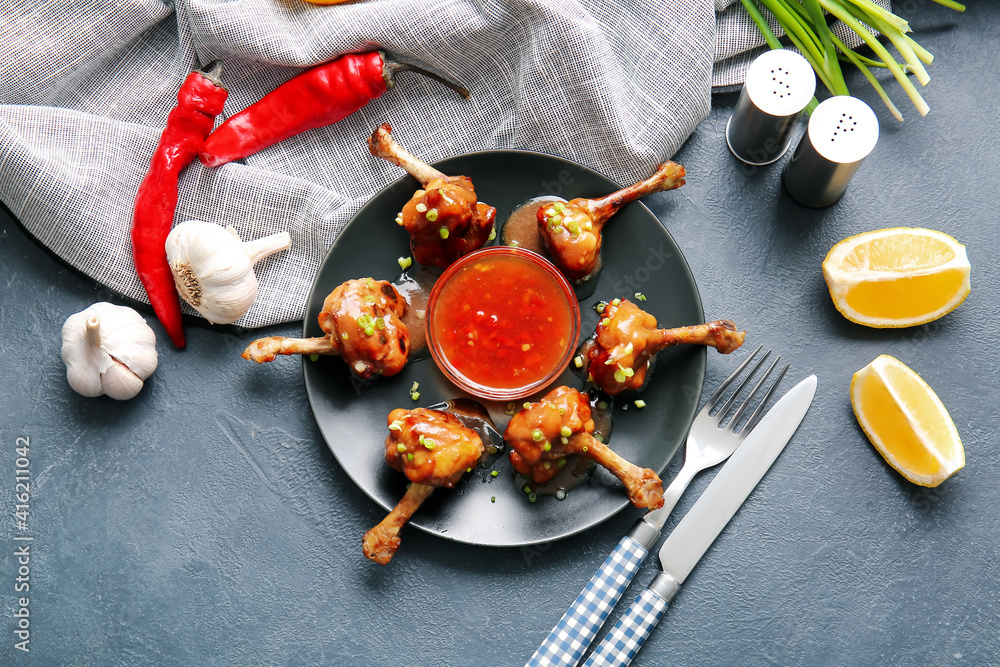 Plate with tasty chicken lollipops on dark background