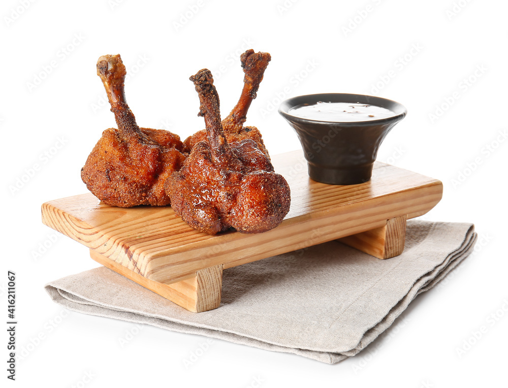 Board with tasty chicken lollipops and sauce on white background