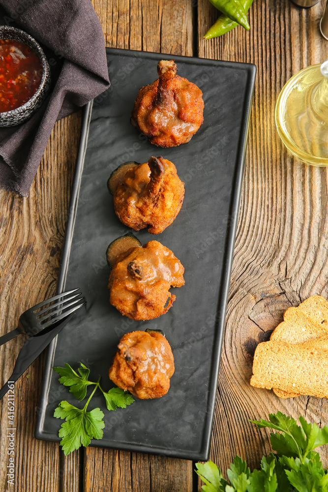 Board with tasty chicken lollipops on wooden background