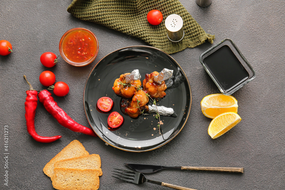 Plate with tasty chicken lollipops on dark background