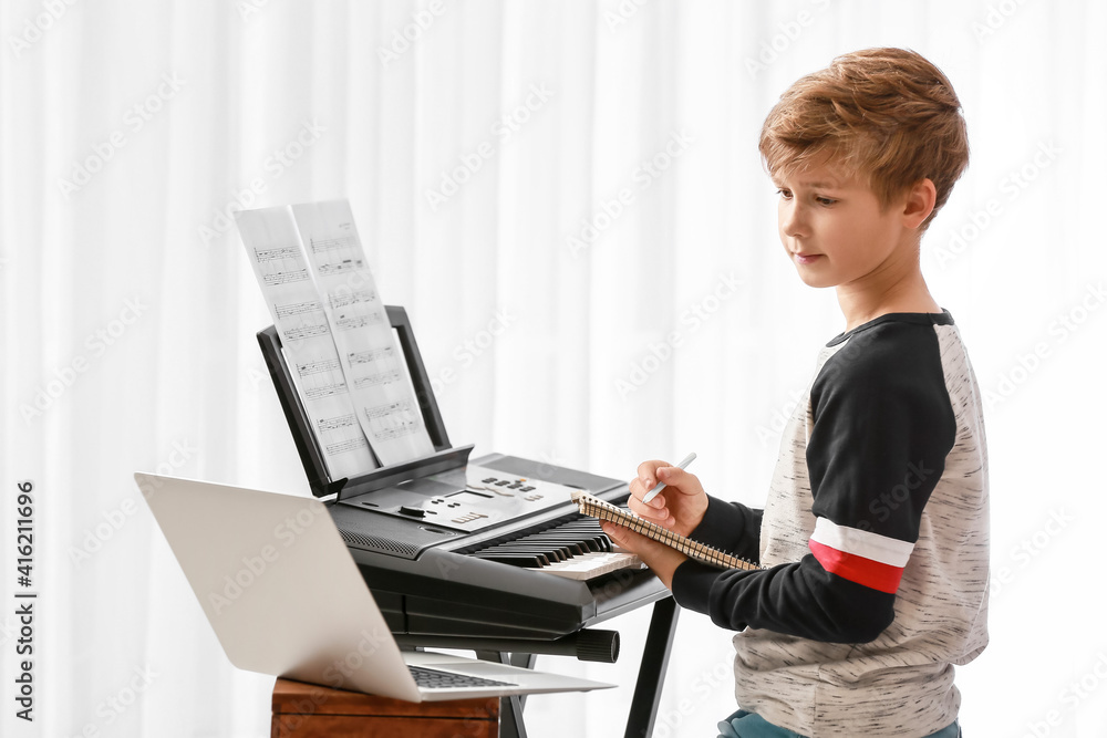 Little boy taking music lessons online at home