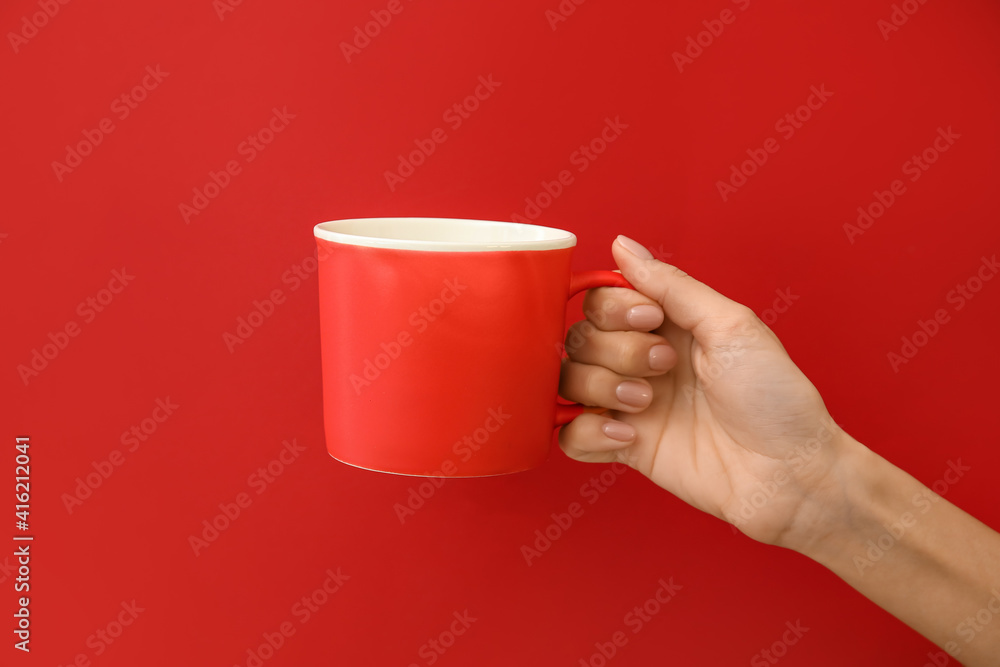 Hand with cup on color background