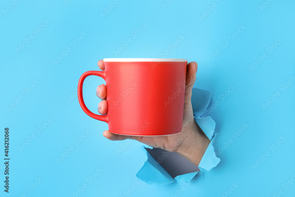 Hand with cup on color background