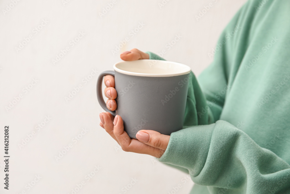 Woman with cup of hot tea on light background