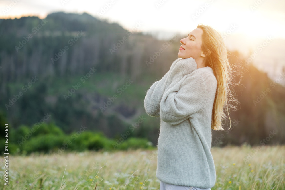 快乐的女人在森林顶峰的绿草上享受日落。新鲜空气，Trave