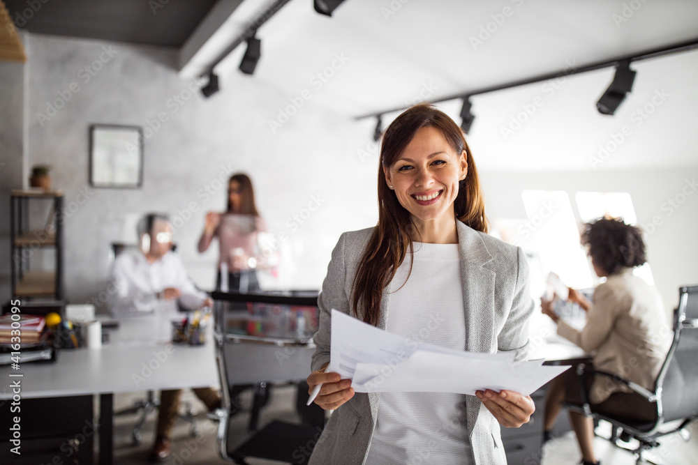 Confident woman, toothy smile, at office.