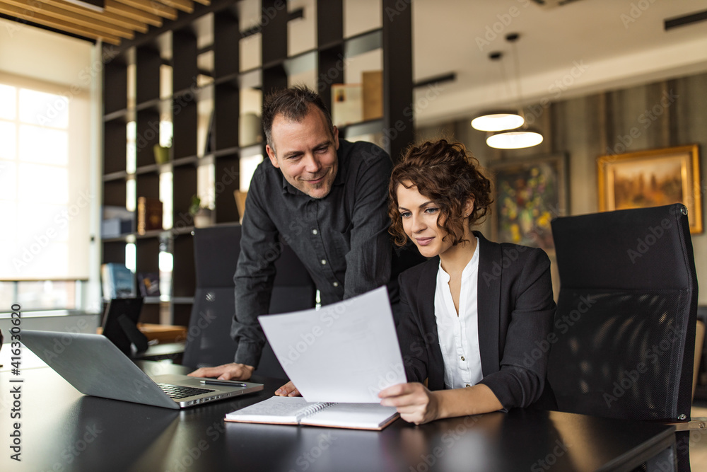 Portrait of a two business executives looking at report with good business results.