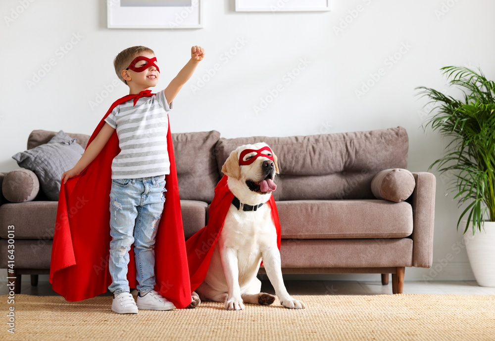 Happy boy and dog in Superhero cloaks playing at home