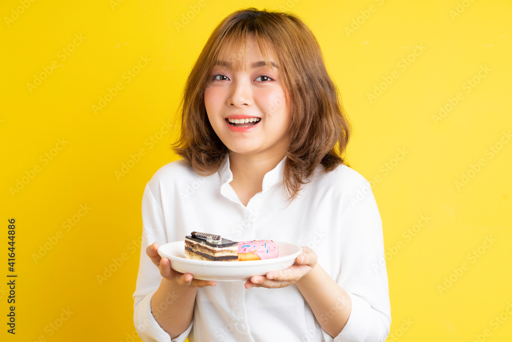 Young Asian girl holding a plate of cake with a cheerful expression