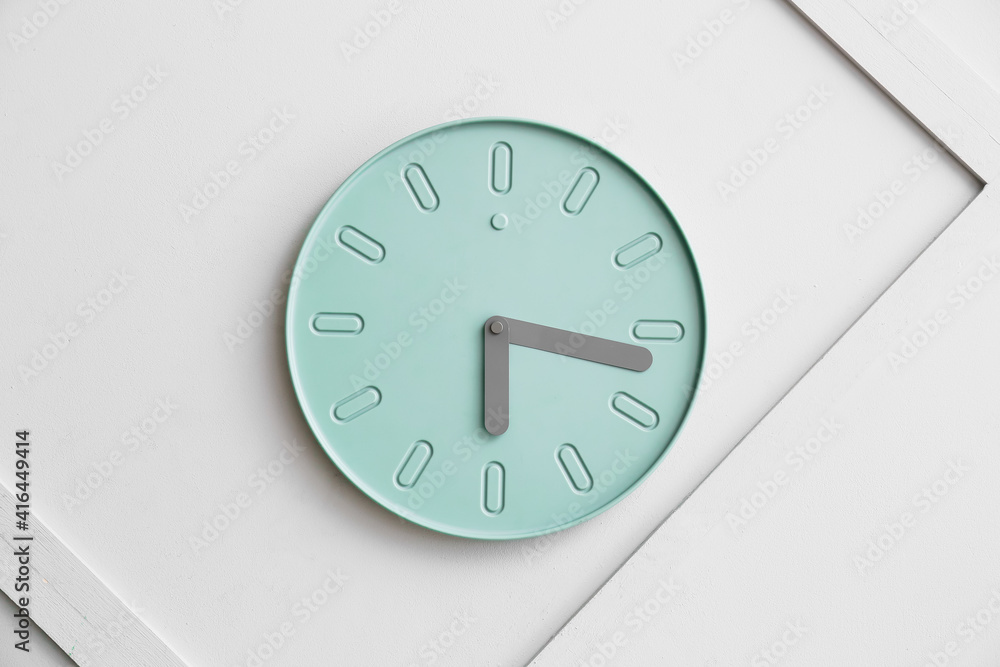 Stylish clock hanging on light wall