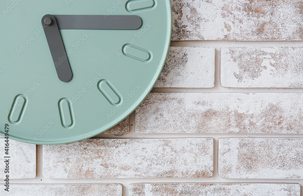 Stylish clock hanging on brick wall, closeup