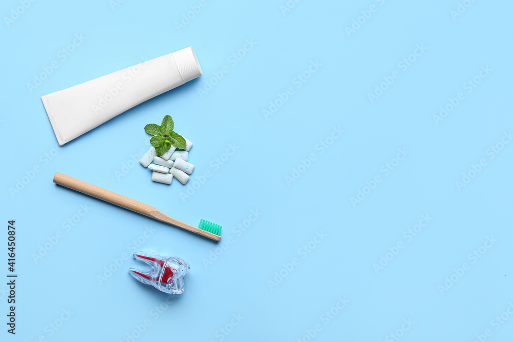 Chewing gums, toothbrush and paste on color background