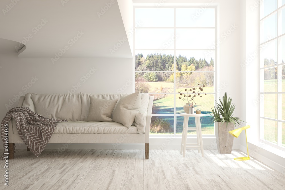 Stylish room in white color with sofa and autumn landscape in window. Scandinavian interior design. 