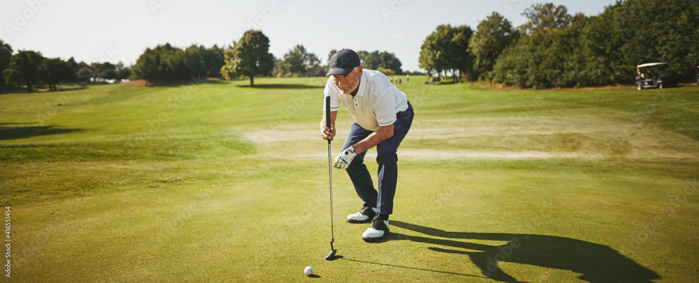 Senior man preparing to putt on a golf green