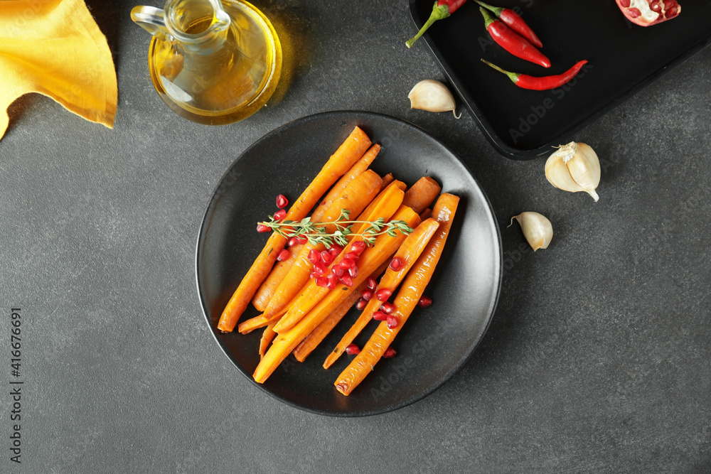 Plate of tasty baked carrot on dark background