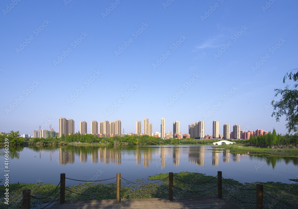 城市建筑在公园湖面上的倒影，蓝天背景，复制空间