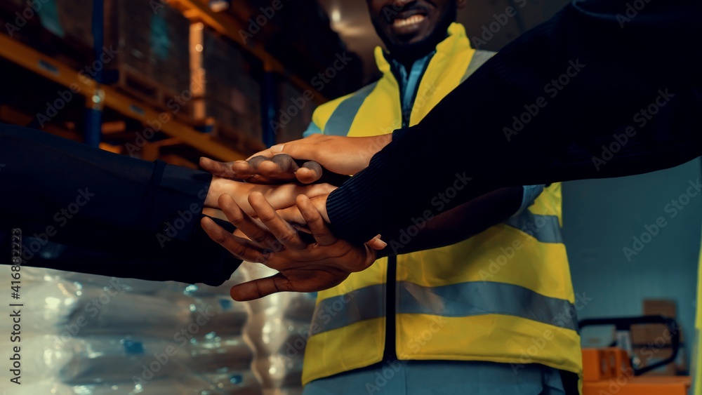 Factory workers stacking hands together in warehouse or storehouse . Logistics , supply chain and wa