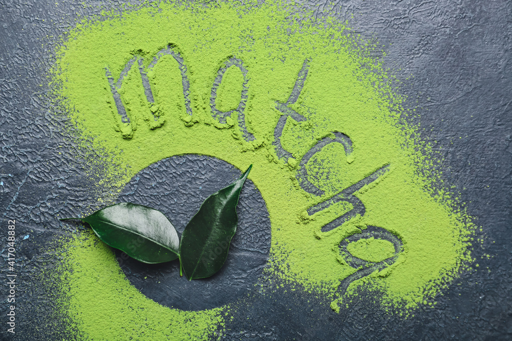 Word MATCHA made of powdered green tea and fresh leaves on dark background