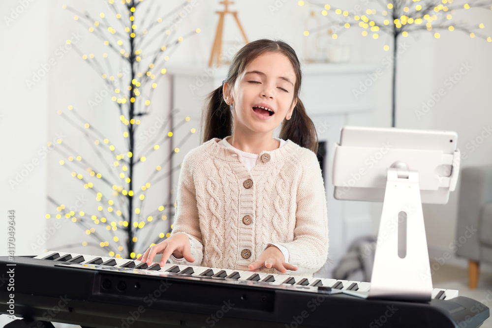 Little girl taking music lessons online at home