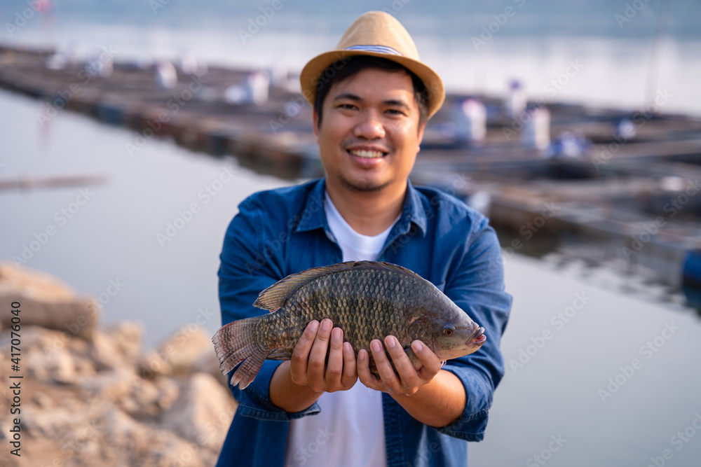 Fisherman holding big tilapia fish, freshwater fish that was raised in ponds and cages.