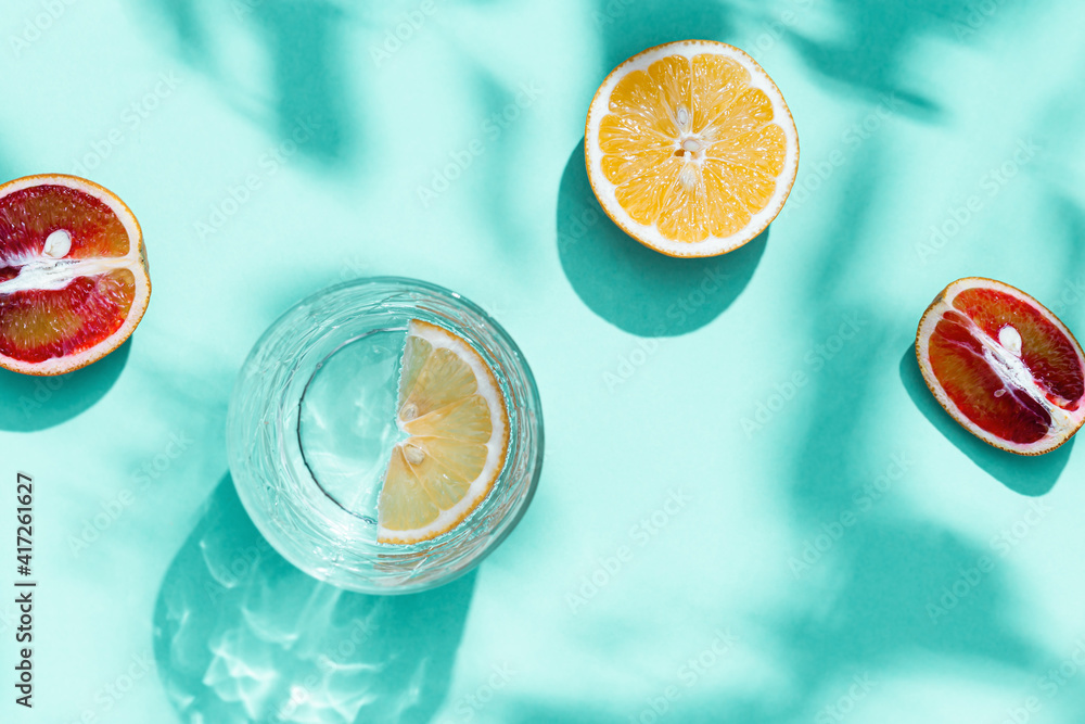 Composition with slices grapefruit, red orange, lemon and drink glass on turquoise color. Summer tim