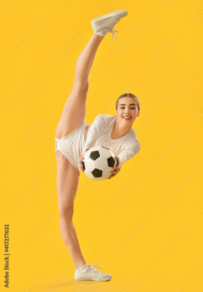 Beautiful cheerleader with soccer ball on color background