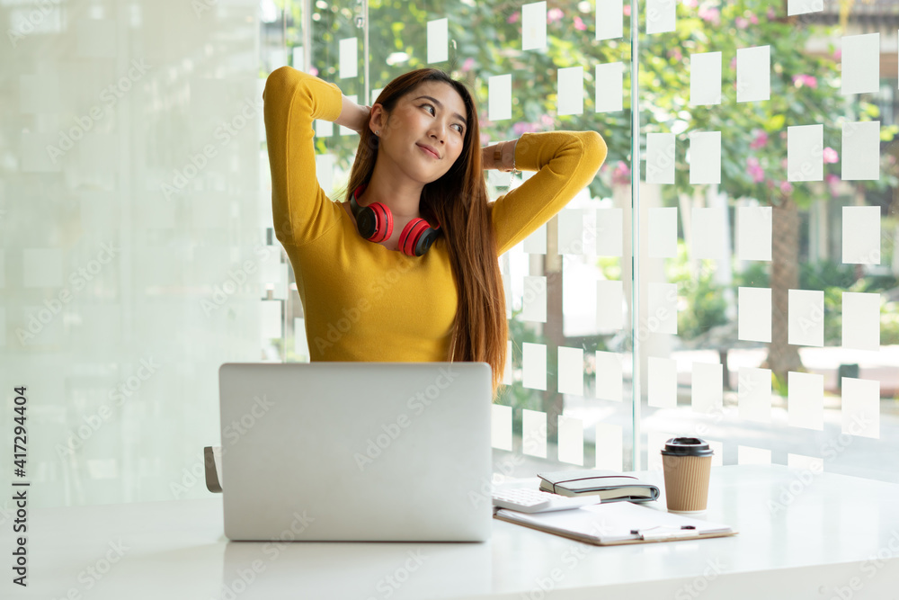 A young woman who is relaxed while working inside the office and listening to her favorite music in 