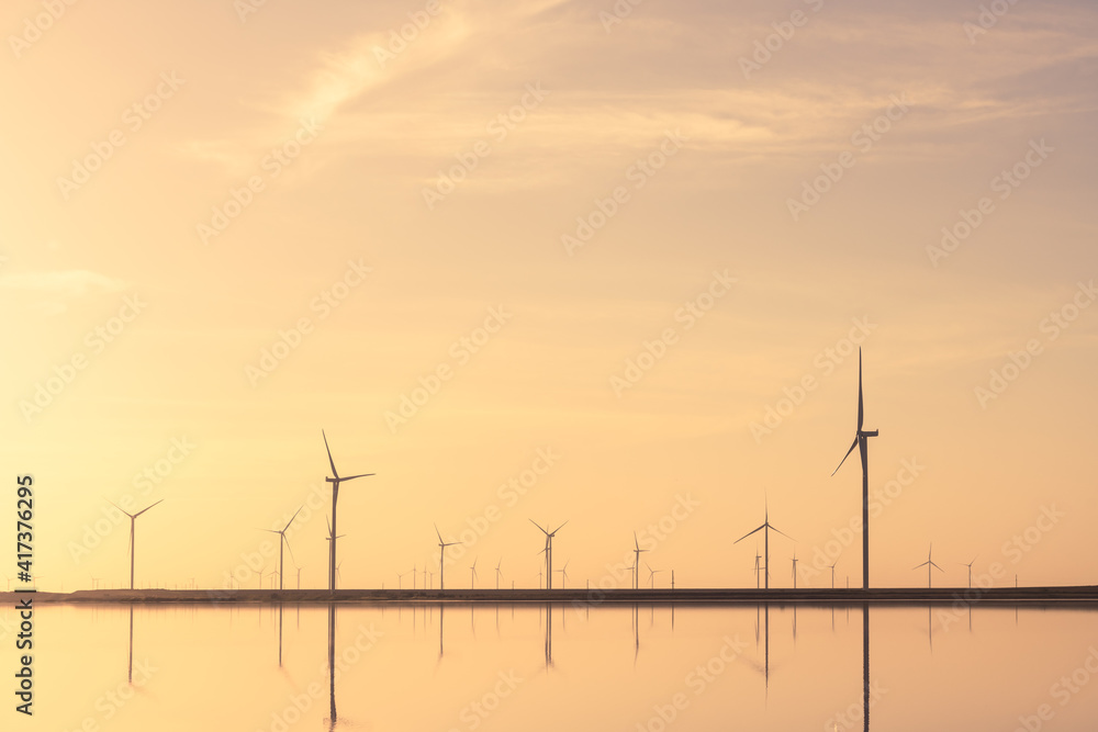 Tranquil minimalist landscape with rows offshore wind turbines, mirrored in the sea water. Industria