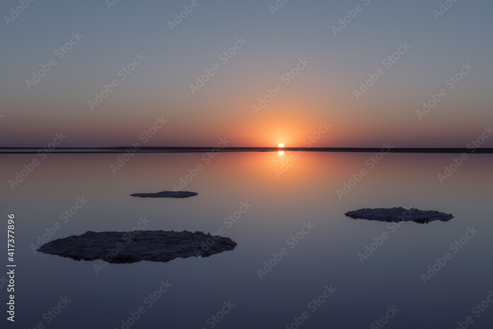 Tranquil minimalist landscape with smooth surface of the pink salt lake with calm water with horizon