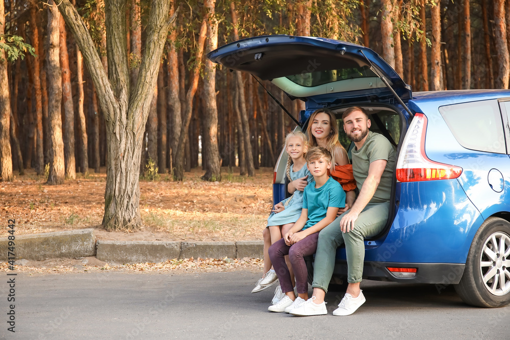 Happy family sitting in car trunk outdoors