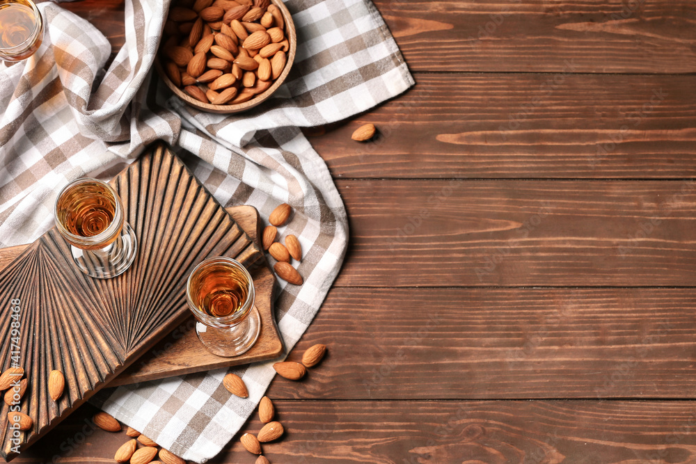 Composition with glasses of almond liquor and nuts on wooden background