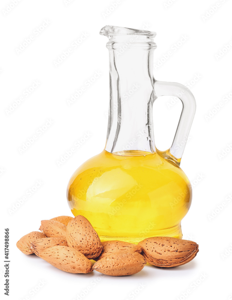 Decanter of almond oil and nuts on white background