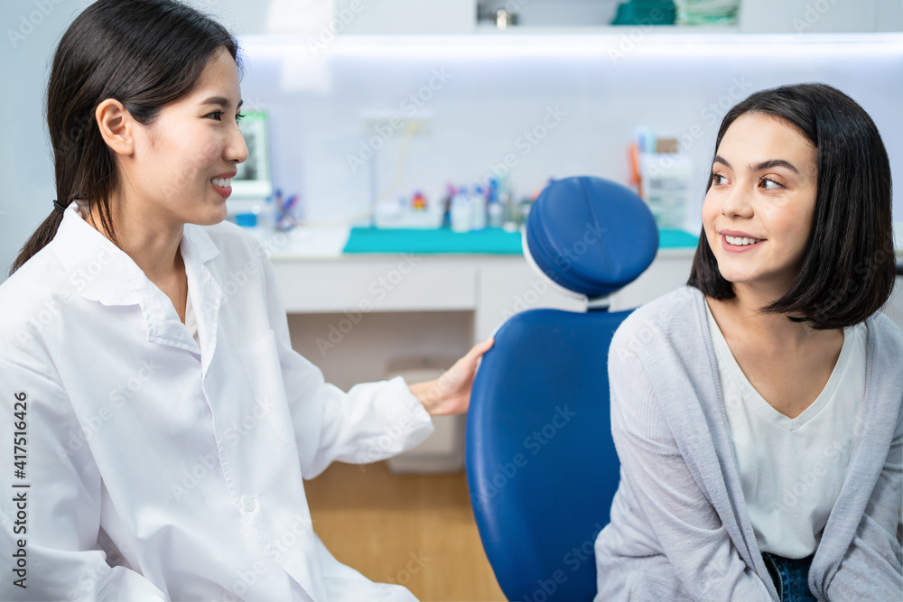 Asian dentist giving advice to patient girl about oral care treatment.