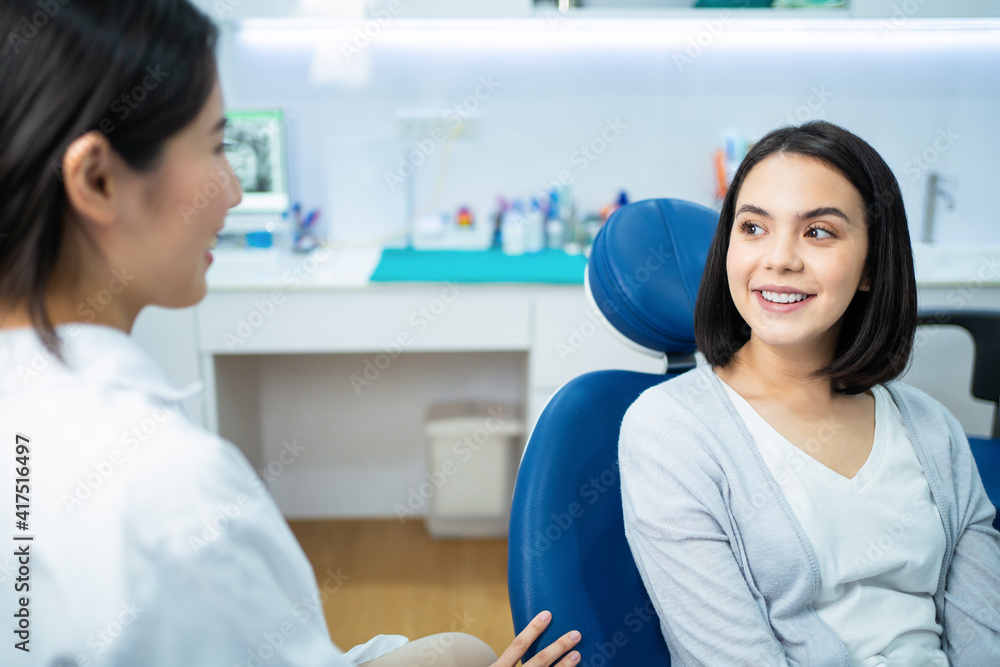 Caucasian girl consulting Asian female dentist about oral care checkup