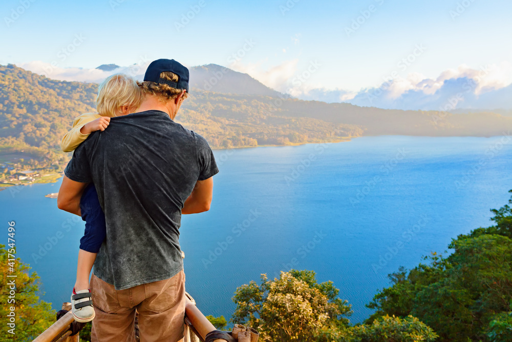 Summer family vacation. Young father with baby son stand at balcony on high cliff. Happy child look 