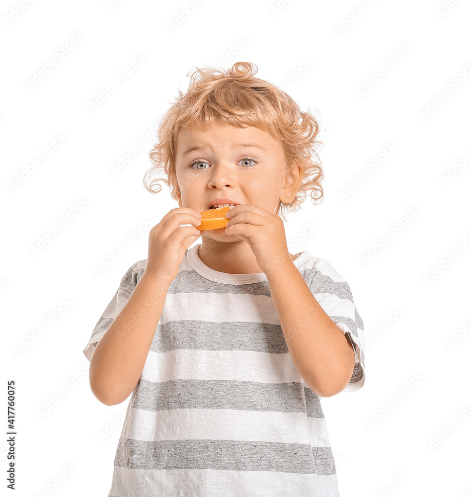 Cute little boy eating orange on white background