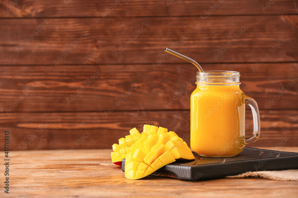 Mason jar of tasty mango smoothie on wooden background