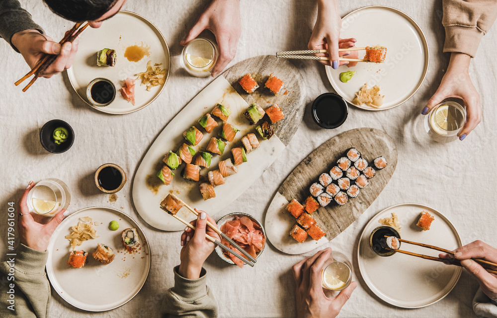 Quarantine Japanese sushi dinner from delivery or takeaway service at home. Flat-lay of people eatin