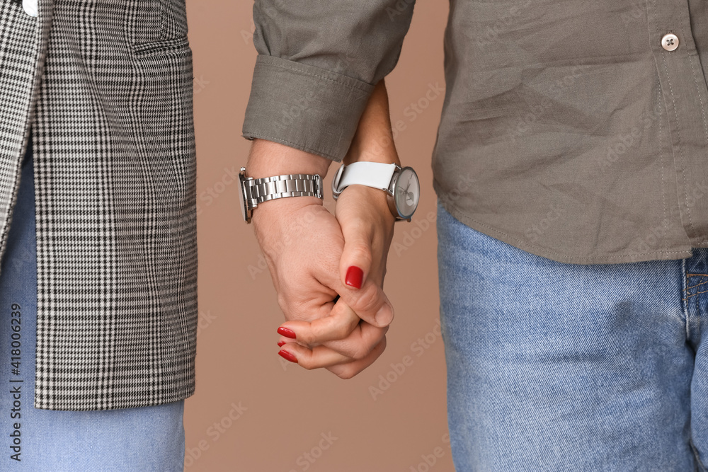 Young couple holding hands on color background