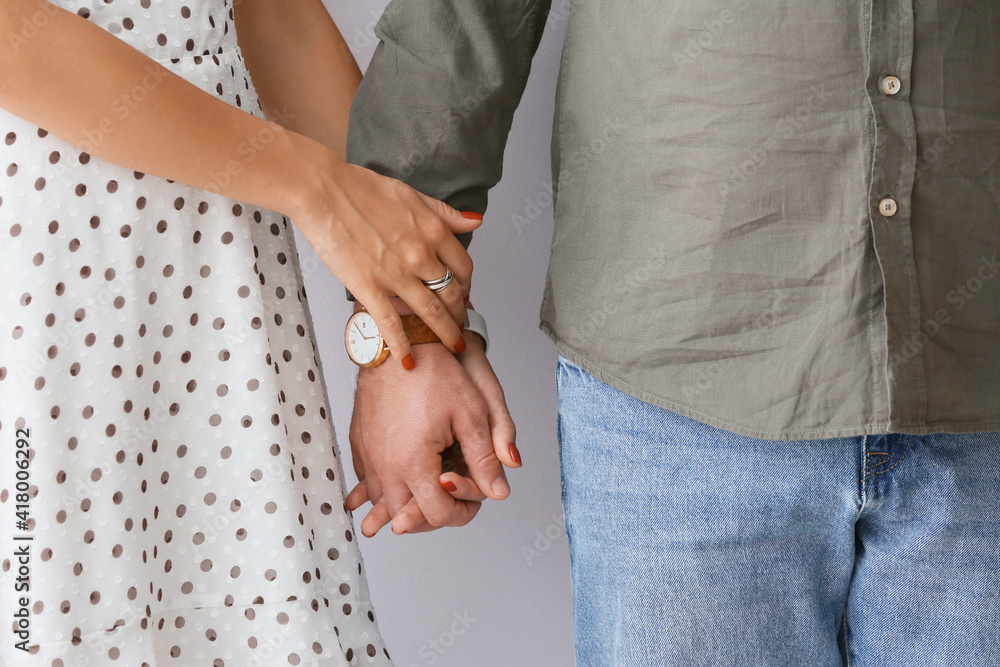 Young couple holding hands on light background