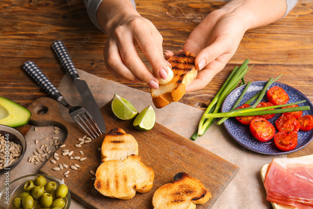 Woman preparing tasty bruschettas on wooden table