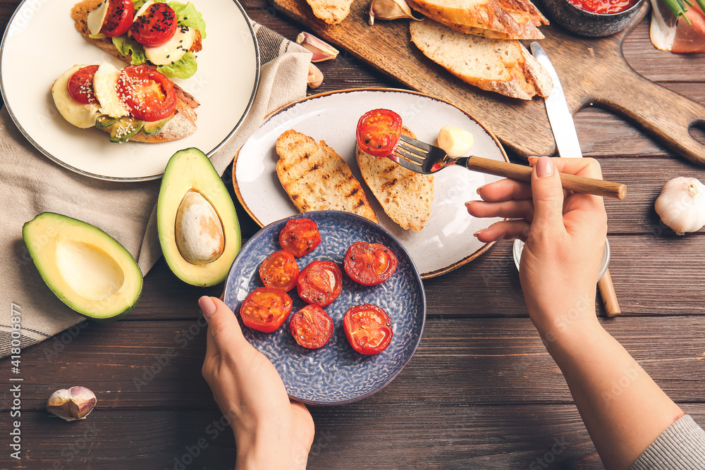 Woman preparing tasty bruschettas on wooden table