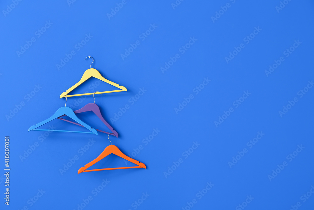 Different clothes hangers on color background