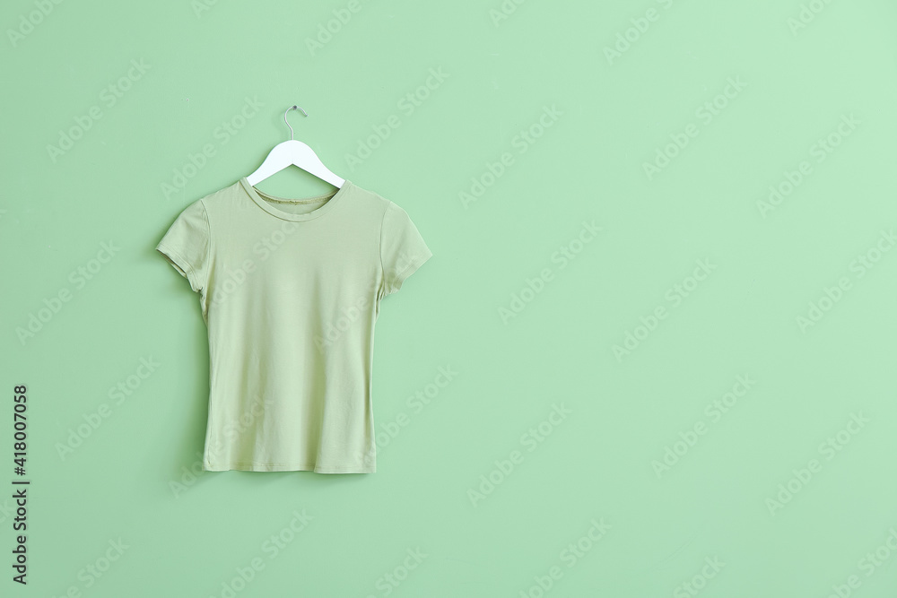 Hanger with t-shirt on color background