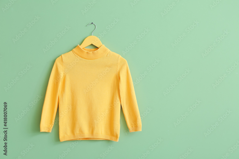 Hanger with sweater on color background